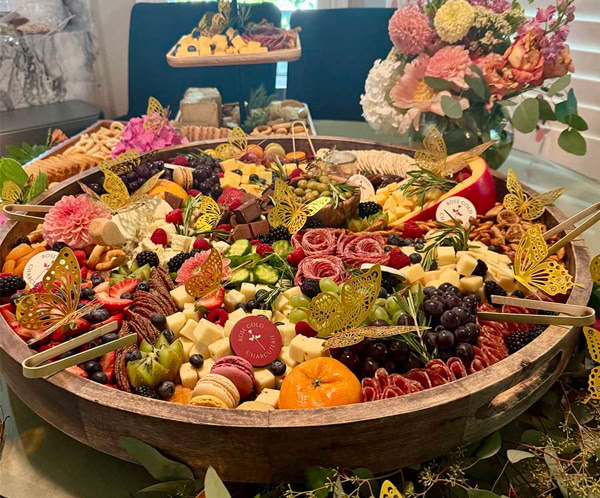 Large custom charcuterie grazing table in San Dimas, CA with cheeses, cured meats, fruit, florals, and decorative serving elements